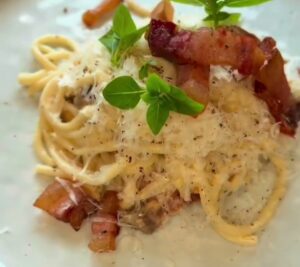 Cremet carbonara med bucatini, sprød guanciale, pecorino og frisk basilikum
