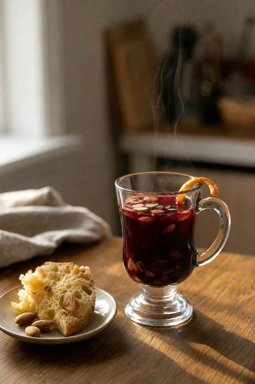 Glas rød gløgg med mandler og rosiner, ved siden af en skive panettone på en tallerken